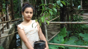 Girl holding a potted tree sapling in Peru